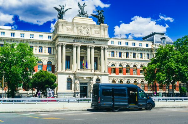 Ministerio de Agricultura showcases grand architecture and vibrant colors in Madrid, with a modern van parked in front.