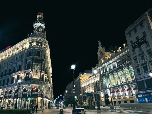 Vibrant night scene featuring illuminated architecture at Teatro Alcázar with decorative buildings lining the street in Madrid.
