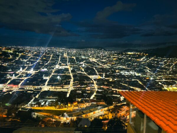 Stunning night view of Quito, Ecuador, showcasing a vibrant skyline illuminated by city lights and surrounding hills.