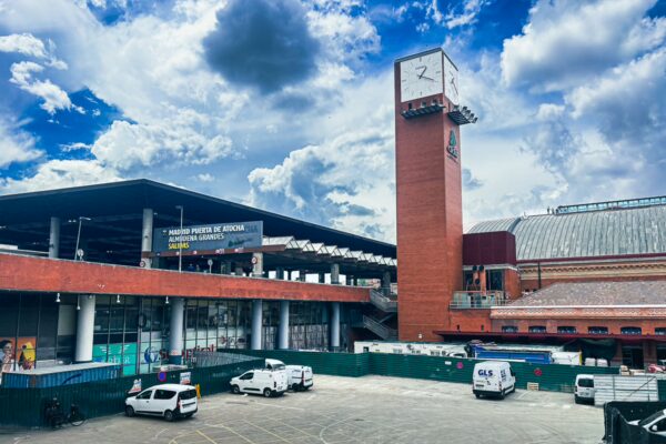 Puerta de Atocha station features a striking modern tower and vibrant signage, set against a dramatic sky in Madrid, Spain.