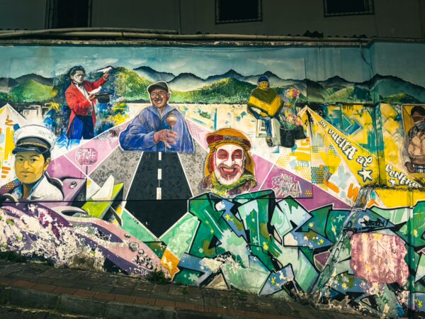 Vibrant street mural featuring colorful portraits and scenes, illustrating local culture in Quito, Ecuador.