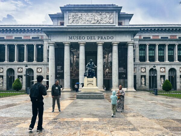 Museo del Prado features elegant architecture, with visitors admiring the iconic facade and statue in front, set in Madrid, Spain.