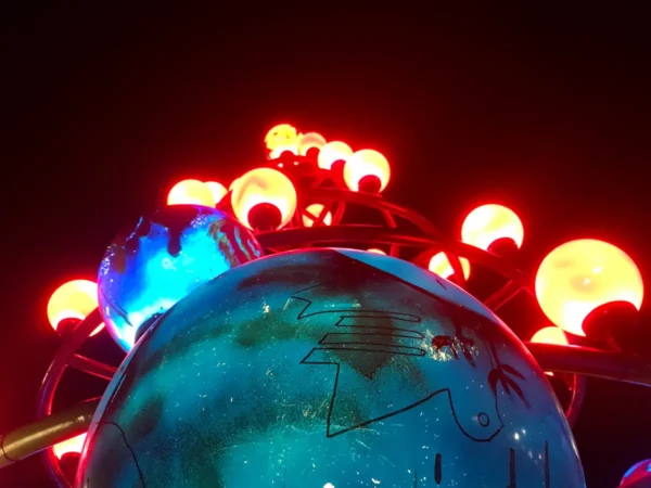 Illuminated orbs glow brightly above a colorful globe feature in Chalkis, showcasing vibrant colors against a dark backdrop.
