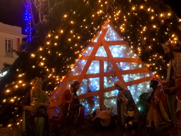 Festive nativity scene with illuminated, decorated tree and vibrant lights in Chalkis during the holiday season.