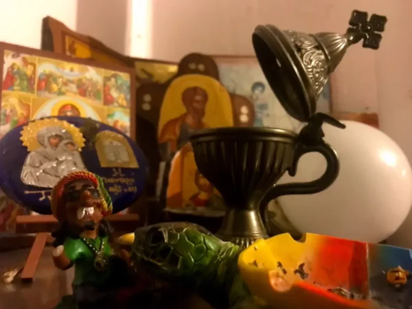 Colorful figurines and religious icons are featured on a wooden surface, with a turtle and a decorative chalice in Chalkis.