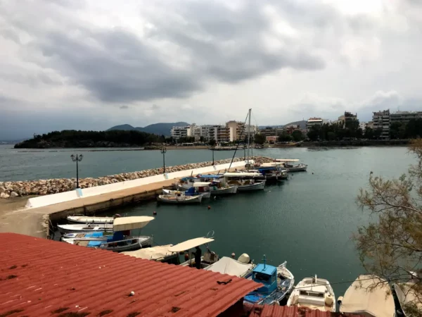 Fishing boats lining the calm waters in Chalkis, with a cloudy sky and coastal buildings in the background.