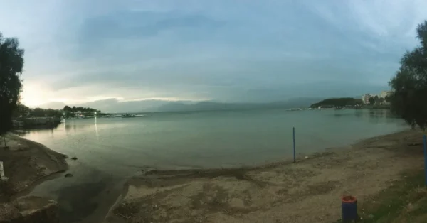 Serene waters at Chalkis showcase a calm beach with soft sands and gentle waves under a moody sky.