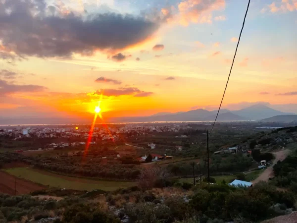 Stunning sunset over Chalkis, casting golden hues across the landscape and highlighting the distant mountains and greenery.