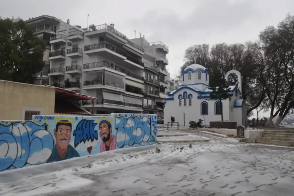 Chalkis features vibrant street art alongside a traditional blue-domed church against a backdrop of modern buildings in Euboea, Greece.