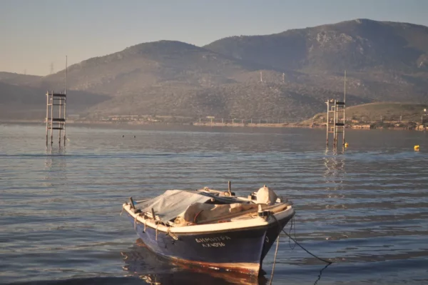 Colorful boat anchored in calm waters with mountains in the background, reflecting the serene beauty of Chalkis, Euboea, Greece.