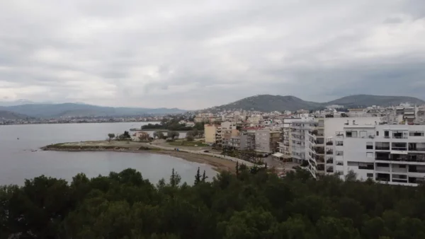Coastal view of Chalkis in Euboea, Greece, featuring modern buildings and a serene waterfront against a cloudy sky.