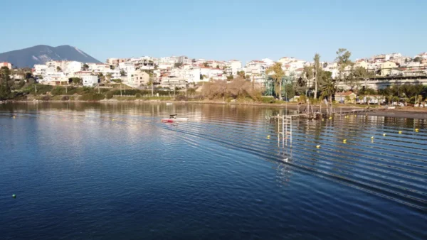 Calm waters reflect the colorful buildings of Chalkis, Euboea, with a small boat creating ripples in the serene scene.
