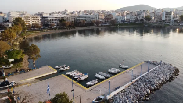 Serene waterfront view with moored boats and calm waters at Chalkis, Euboea, Greece, framed by a backdrop of city buildings.