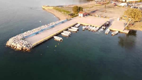 Chalkis harbor features a serene waterfront with fishing boats docked alongside a stone pier in Euboea, Greece.