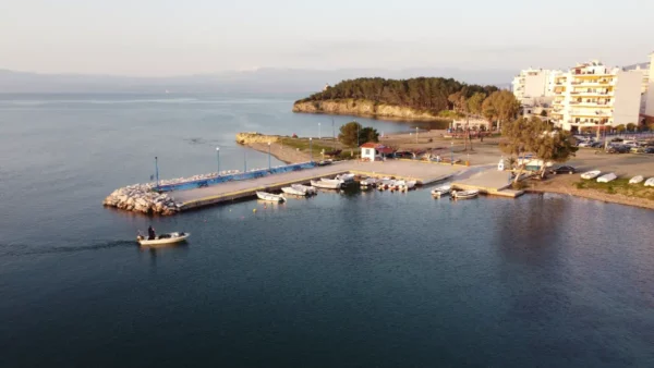 Serene Chalkis harbor in Euboea, Greece, features colorful boats moored at the dock with a coastal landscape in the background.