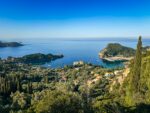 Coastal landscape in Corfu, Greece, with blue sea, rocky coves, and a hillside viewpoint overlooking the water.