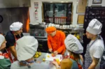 Cooking-class session in Salento, Colombia, chefs in aprons guide guests chopping on a prep table.
