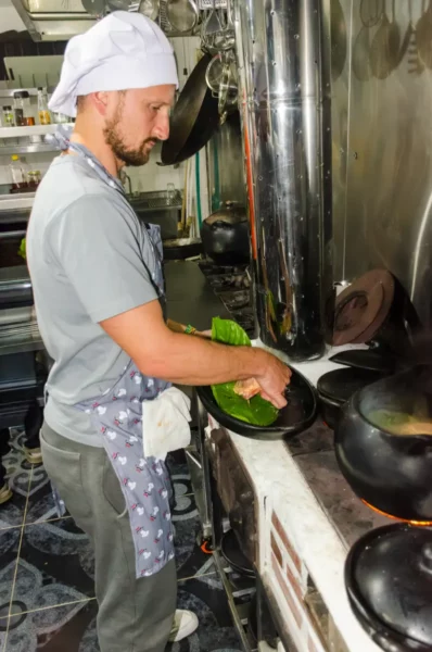 Chef in a cooking class in Salento, Colombia, preparing food at a large stove with cookware