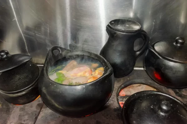 Cooking-class cookware simmering in Salento, Colombia—black clay pots over flame and steam