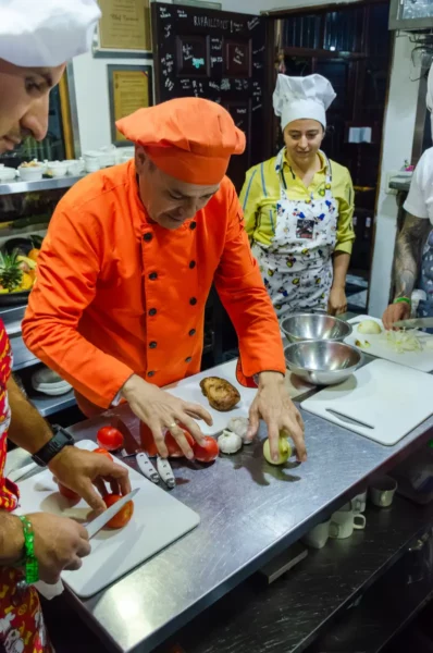 Chef prepping vegetables during a cooking class in Salento, Colombia, with other chefs watching