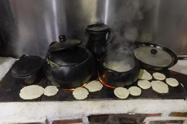 Cooking class cookware on a stove in Salento, Colombia: black pots, lids, and tortillas cooking over flames