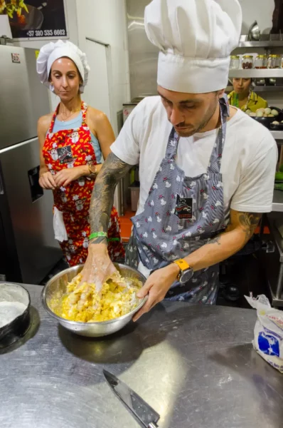 Chef mixing ingredients in cooking class in Salento, Colombia; kitchen sign reads +57 310 585 6662.