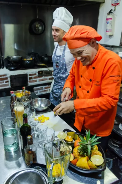 Chefs in cooking class prep food in an orange jacket kitchen, Salento, Colombia
