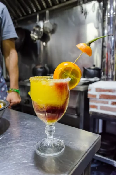 Cooking class cocktail in Salento, Colombia, with orange slices and chili garnish on a bar counter.