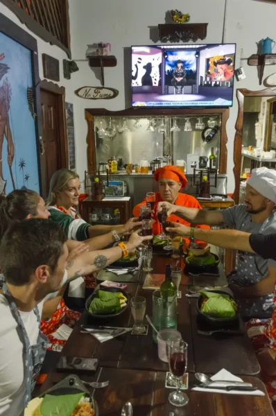 Cooking class in Salento, Colombia: friends toast drinks at a bar with a “No Fumes” sign.