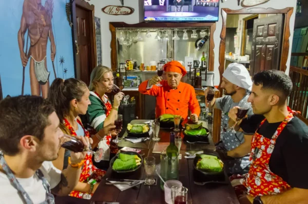 Chef in orange hat leads a cooking class in Salento, Colombia, as diners taste and drink at the table