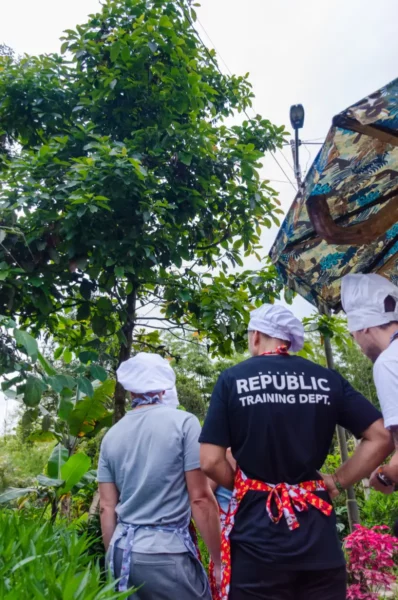 Cooking class in Salento, Colombia: chefs in aprons with “REPUBLIC TRAINING DEPT.” near hanging plants