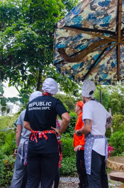 Cooking class group in Salento, Colombia, wearing chef hats and aprons under a patterned canopy